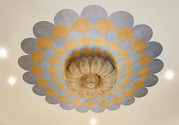 A ceiling painted with Modern Masters - Metallic Paint in gold and gray scalloped patterns surrounds a woven circular light fixture at the center, complemented by nearby recessed lighting.