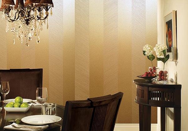 A dining room with a wooden table set for four and a chandelier, featuring a console table with white flowers, grapes, and apples against beige striped walls painted with Modern Masters Metallic Paint for subtle shimmer.