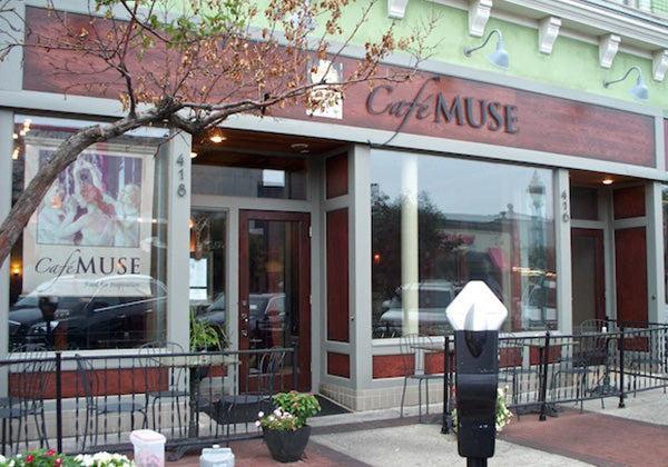 Street view of Café Muse with large windows, outdoor seating, potted plants, and a parking meter. The cafés name is displayed in elegant lettering above the entrance, protected by Modern Masters - Masterclear Supreme for lasting brilliance.
